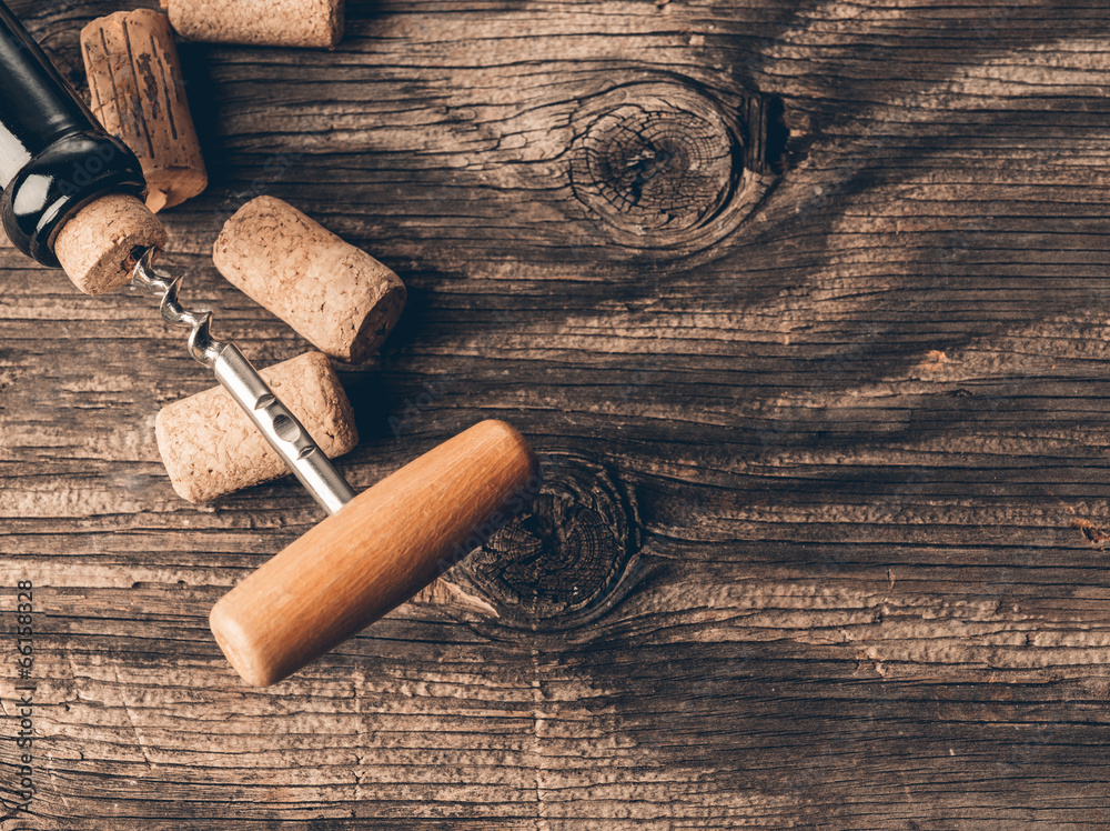 Bottle of wine and corkscrew on wooden background