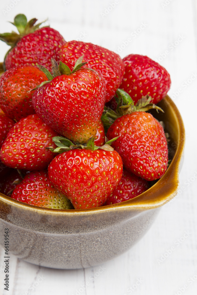 Fresh organic strawberries in bowl on white wooden background Fresh organic strawberries in bowl on white wooden background
