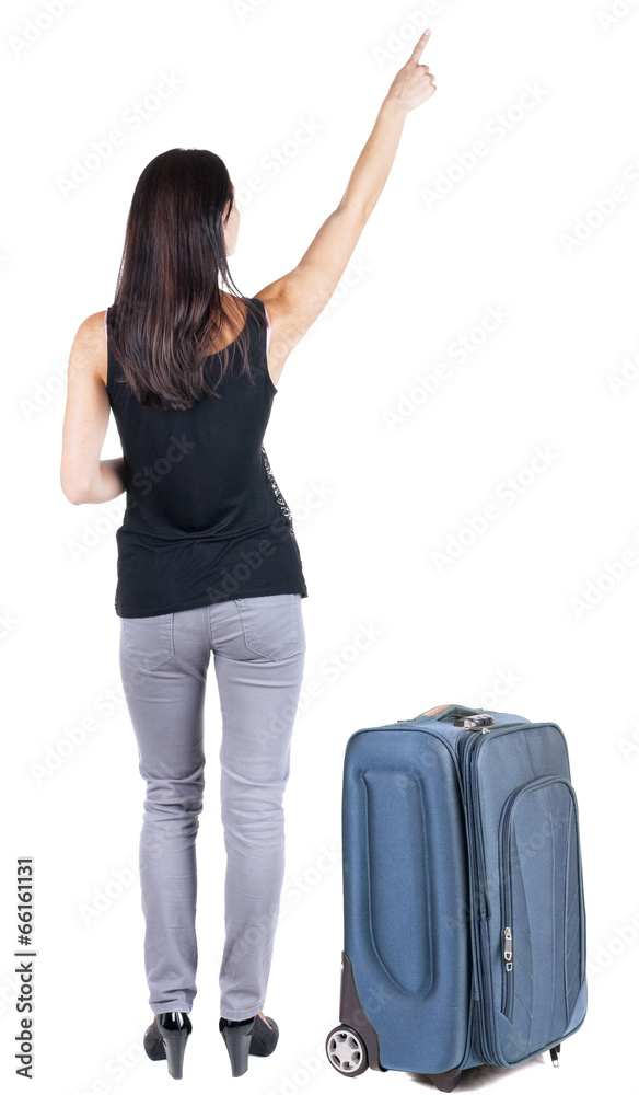 Back view of young brunette woman traveling with suitcas and poi Back view of young brunette woman traveling with suitcas and poi