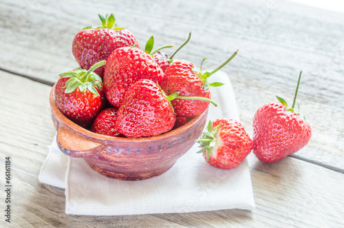 Fresh strawberries in the bowl on the wooden table