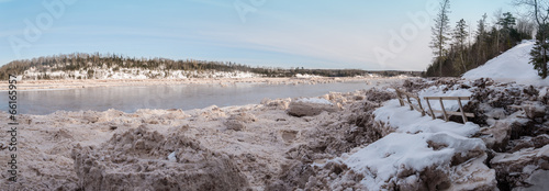 Panorama of forest river covered with snow and ice