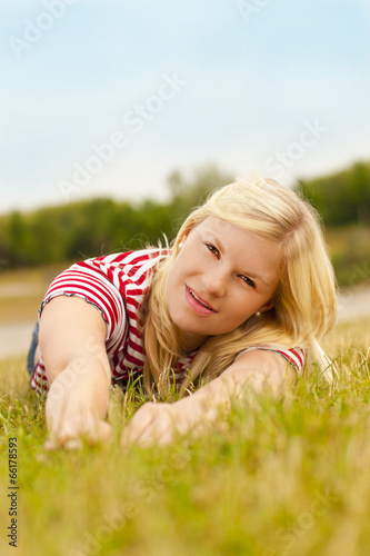 Junge blonde Frau im Gras liegend