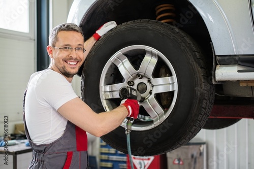 Cheerful serviceman unscrewing wheel in car workshop © Nejron Photo