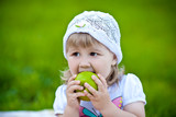 Девочка кушает яблоко на природе