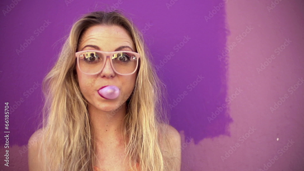 Young woman blowing a pink bubble gum