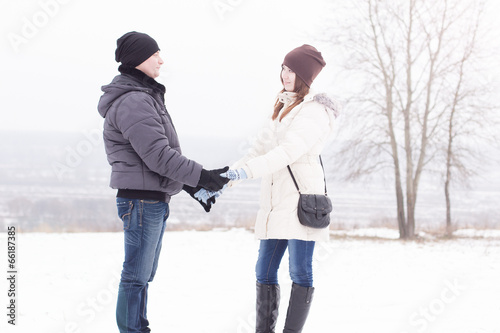 Young couple in winter park holding hands
