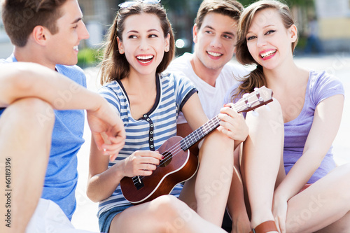 Young woman playing ukulele for friends © pikselstock