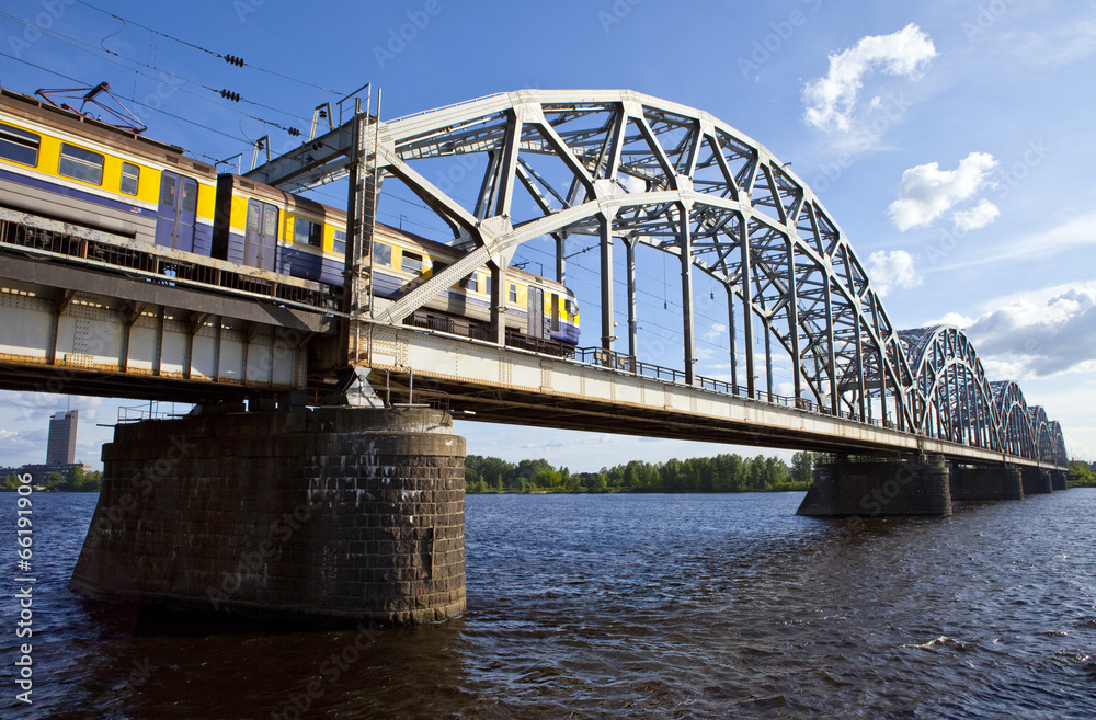 Naklejka premium Train Crosses the Iron Bridge over the Daugava River in Riga