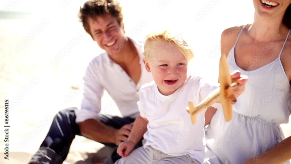 Family playing on beach with toy plane Family playing on beach with toy plane