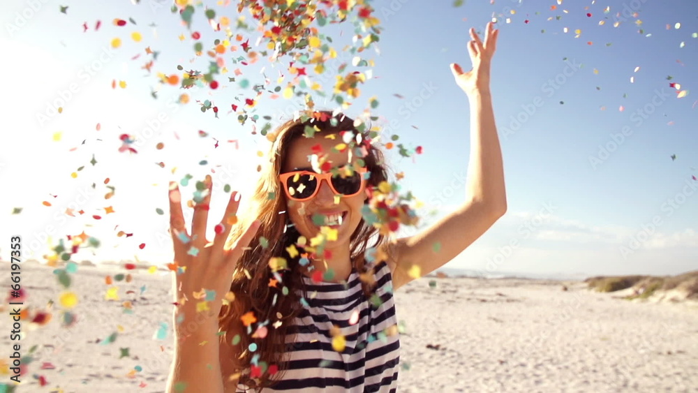 Woman throwing confetti in slow motion on the beach