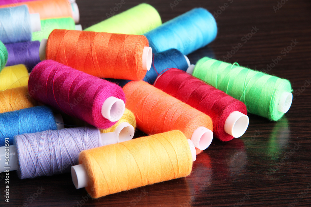 Multicolor sewing threads on wooden background Multicolor sewing threads on wooden background