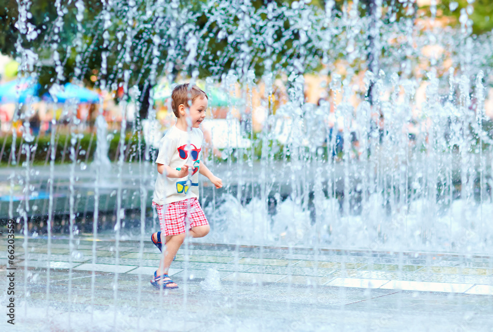 Obraz premium excited boy running between water flow in city park