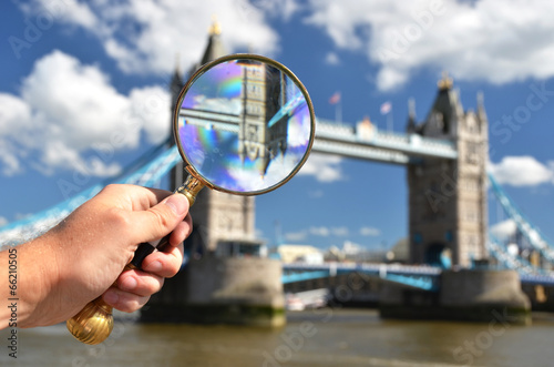 Magnifying glass in the hand against Tower bridge in London