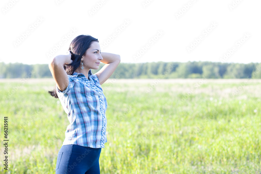 Woman in shirt looks into the distance outdoors