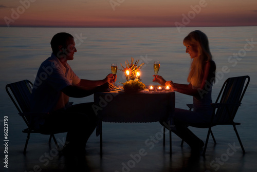 A young couple share a romantic dinner with candles on the beach © EMrpize