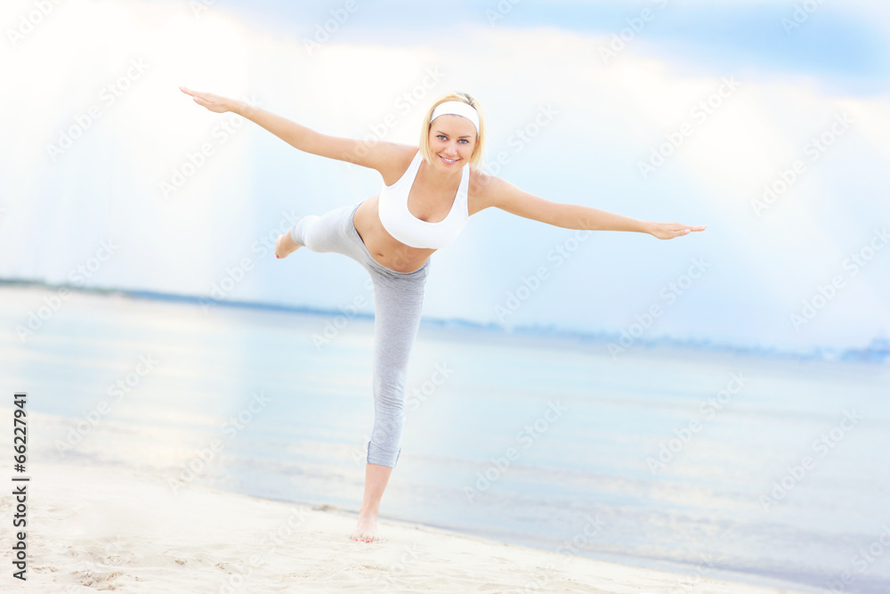 Fototapeta premium Young woman exercising on the beach