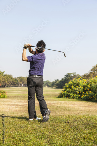 Male golf player teeing off golf ball from tee box