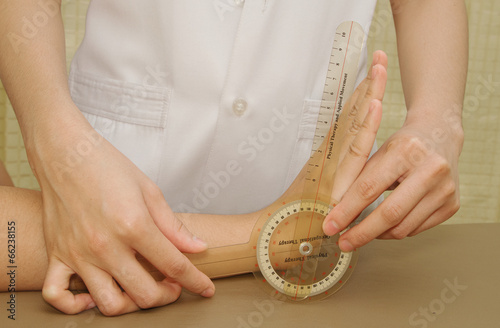 Fotografie Physiotherapist examining patients wrist with goniometer
