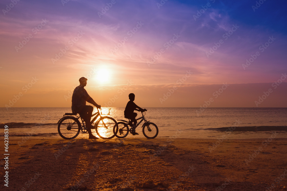father and son at the beach on sunset,Biker family silhouette