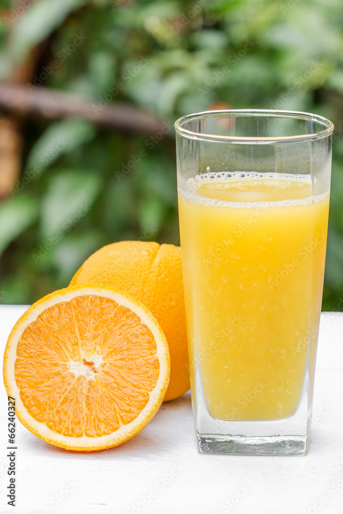 Glass of freshly pressed orange juice with sliced orange on woo Glass of freshly pressed orange juice with sliced orange on woo