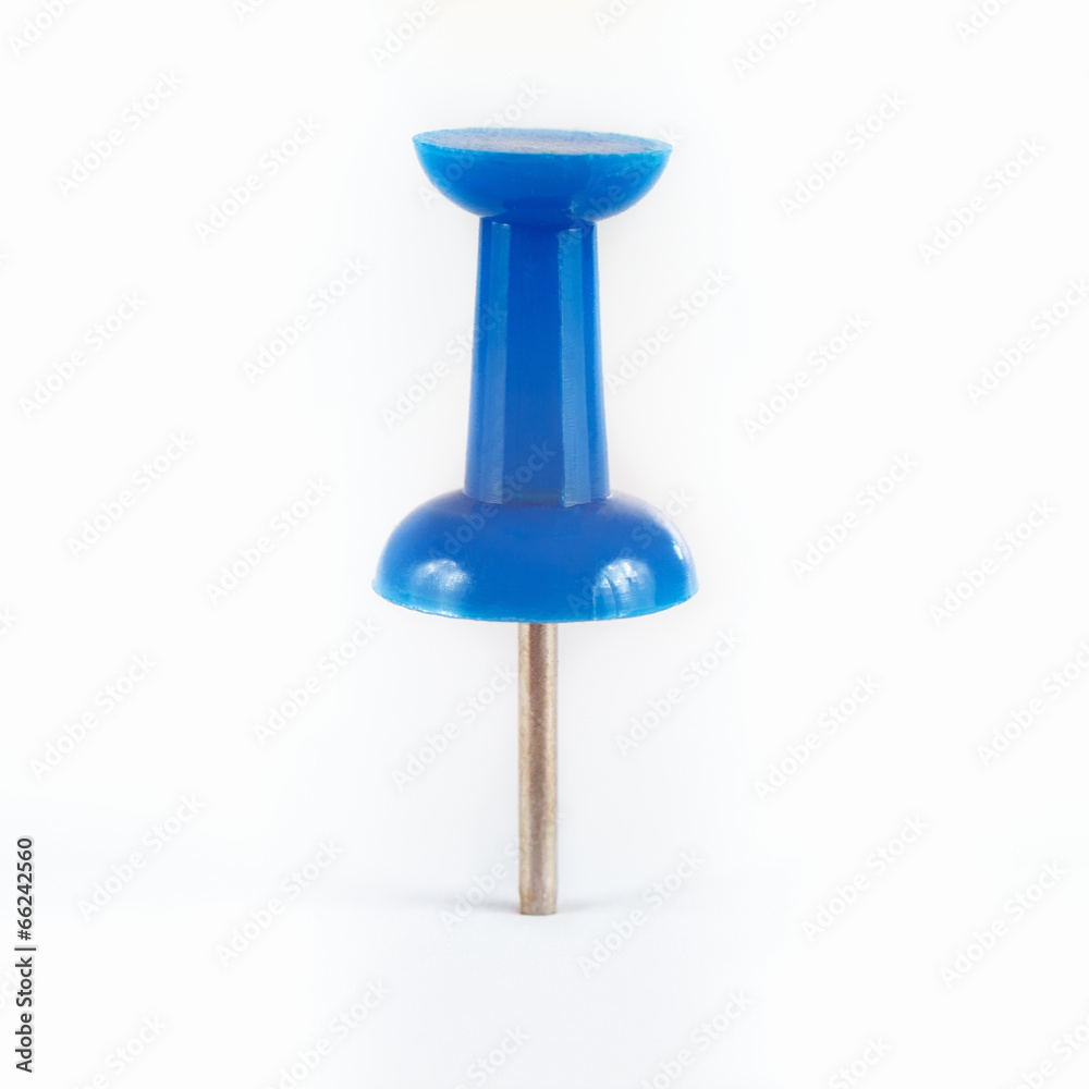 Blue pushpin stuck in the white paper close up