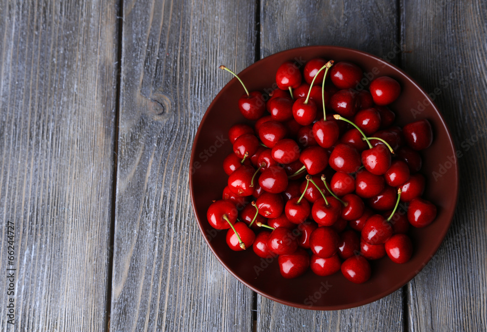 Sweet cherries on plate on wooden background Sweet cherries on plate on wooden background