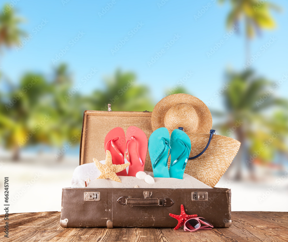 Old suitcase with accessories on beach - obrazy, fototapety, plakaty 