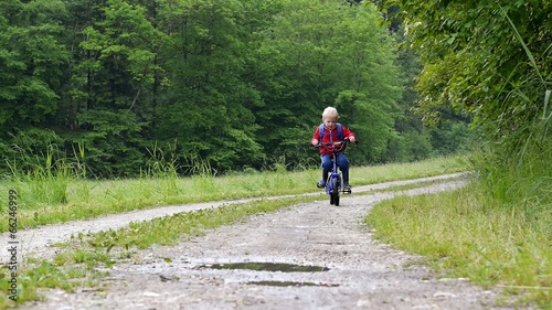 slow motion of boy crossing  a puddle with the bike