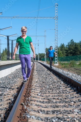 Two young men walking on the rail track