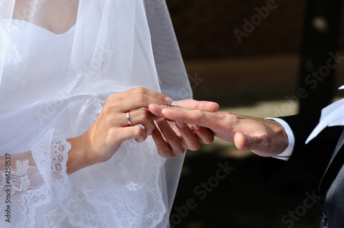 Bride putting a wedding ring on a groom's finger