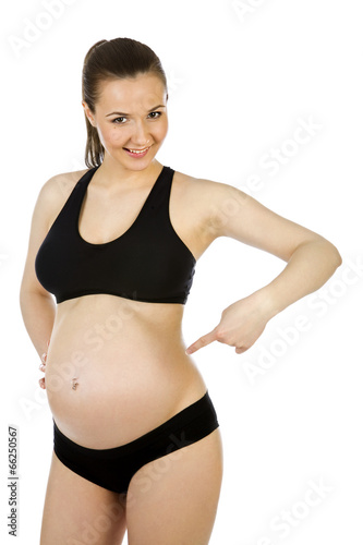Beautiful pregnant woman pointing finger to her belly on white 