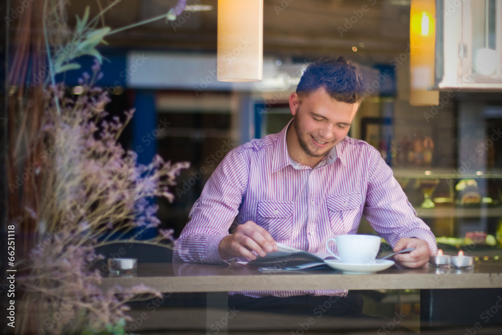 Fototapeta premium Portrait of a young man reading and drinking coffee