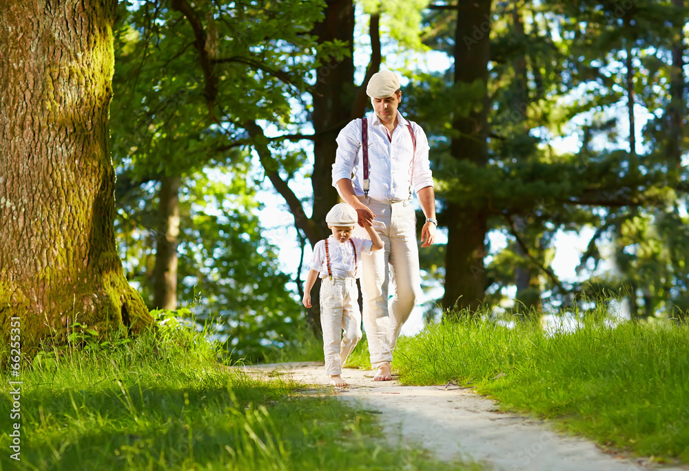 Fototapeta premium father and son walking the forest sunlit path