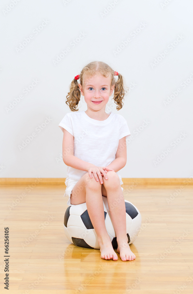 Little cute girl sitting on the soft ball.
