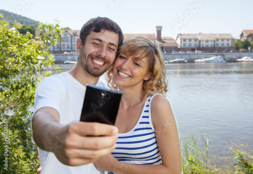 Laughing couple on the river taking a selfie