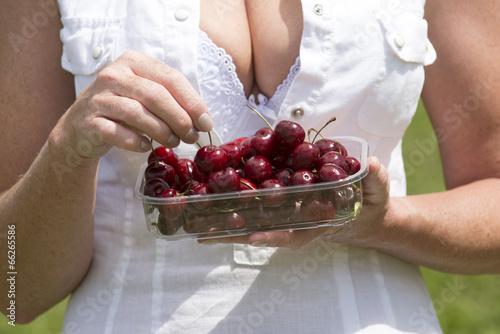 Photos Woman eating cherries from a punnet