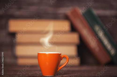 Books and cup of coffee on wooden background. photo