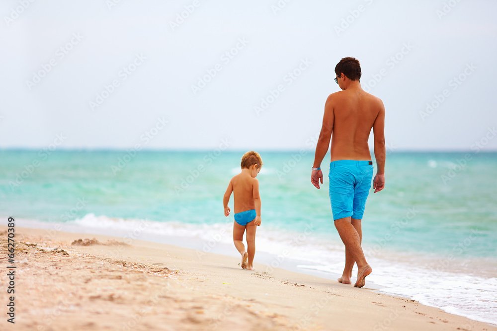 father and son walking the sea beach