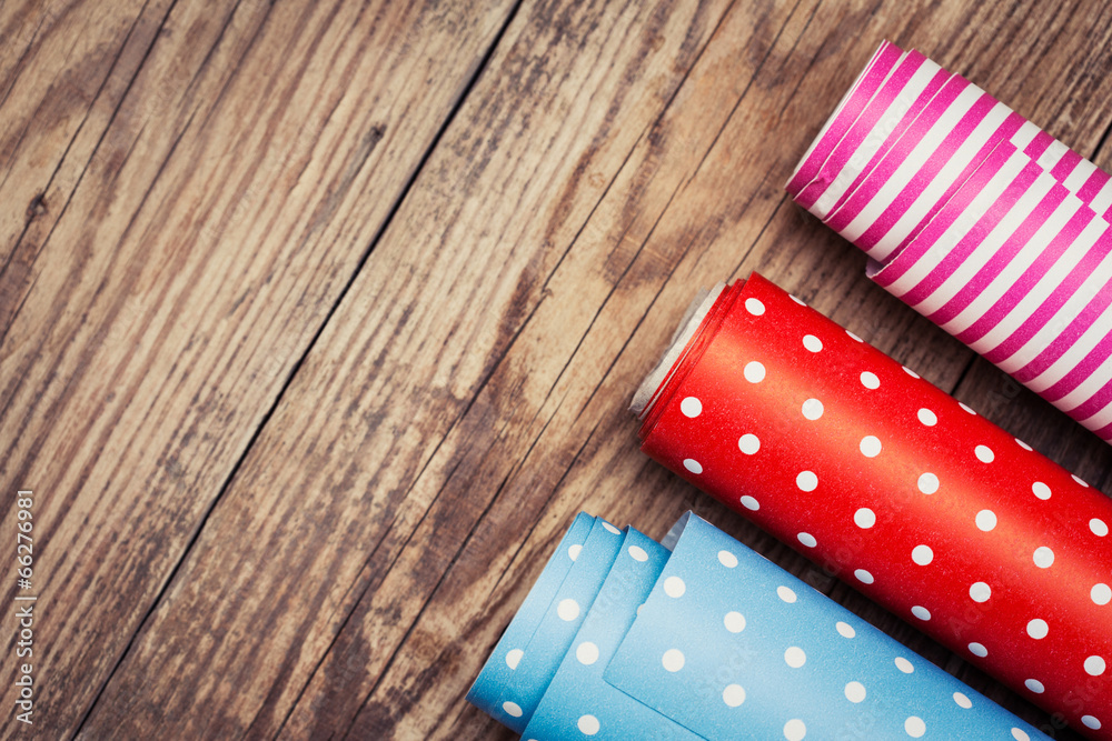 Obraz premium Rolls of colored wrapping paper on wooden background