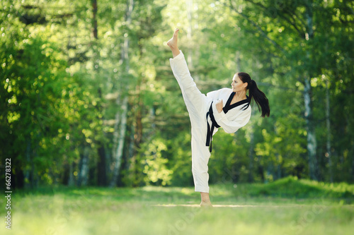 Karate girl makes high kick on forest outdoor location photo