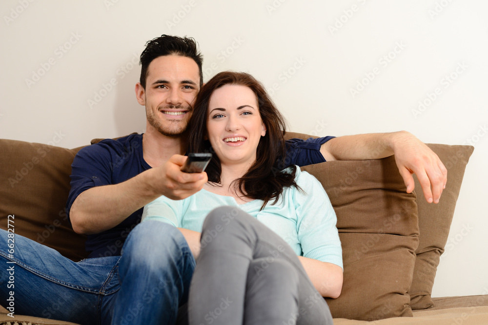 happy lovely young couple at home in sofa watching tv together happy lovely young couple at home in sofa watching tv together
