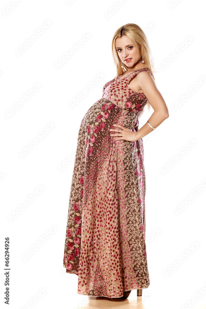 Pregnant woman in a long dress posing on a white background