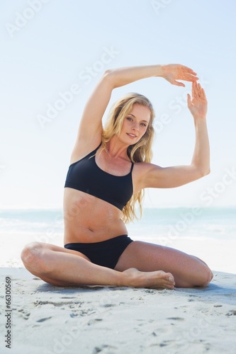 Fit blonde in yoga pose on the beach smiling at camera © WavebreakmediaMicro