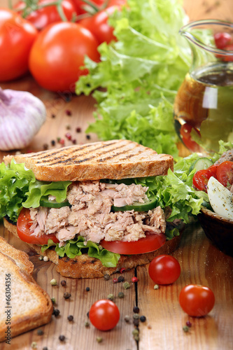 Sandwich with tuna and salad on wood background