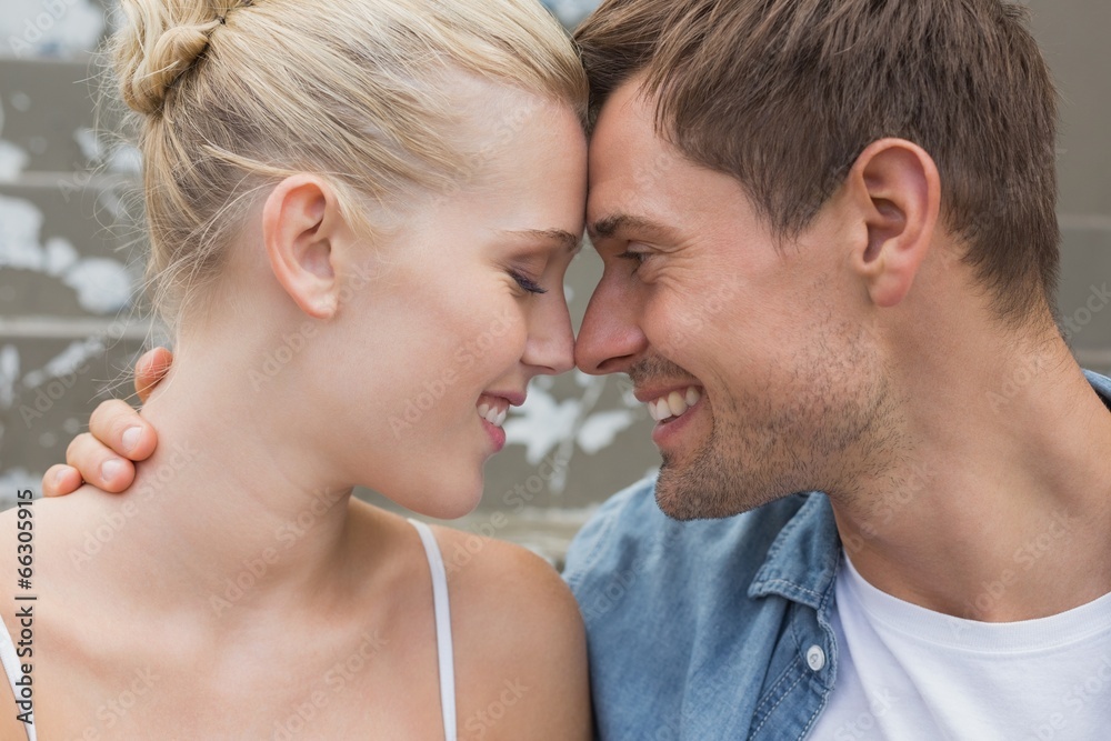 Hip young couple sitting on steps smiling at each other Hip young couple sitting on steps smiling at each other