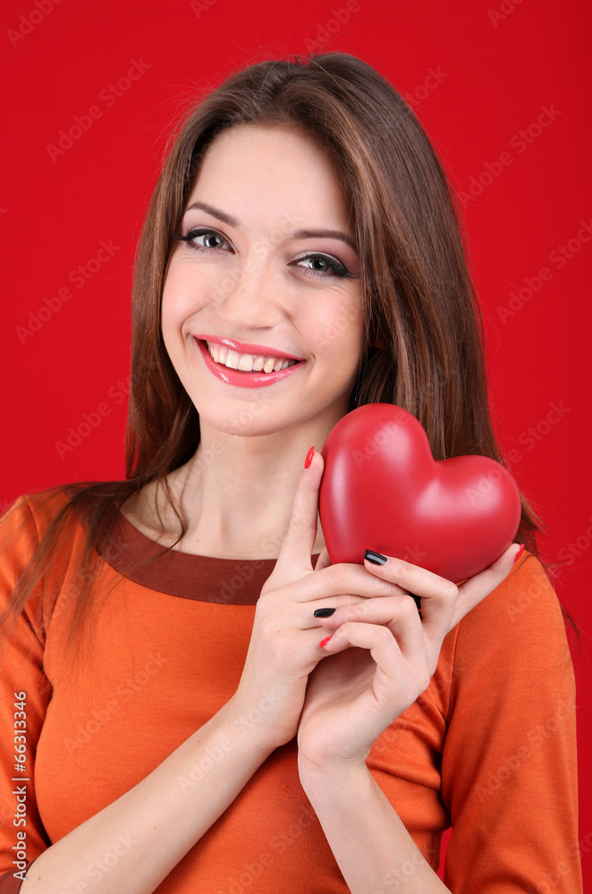 Attractive woman with heart, on red background Attractive woman with heart, on red background