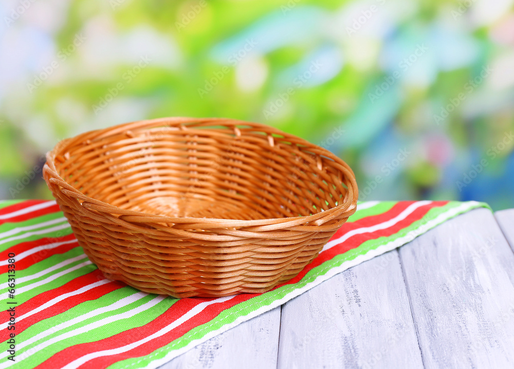 Empty wicker basket on wooden table, on bright background Empty wicker basket on wooden table, on bright background