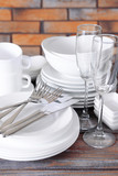 Set of white dishes on table on brick-wall background