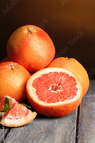 Ripe grapefruits on wooden board, on dark color background