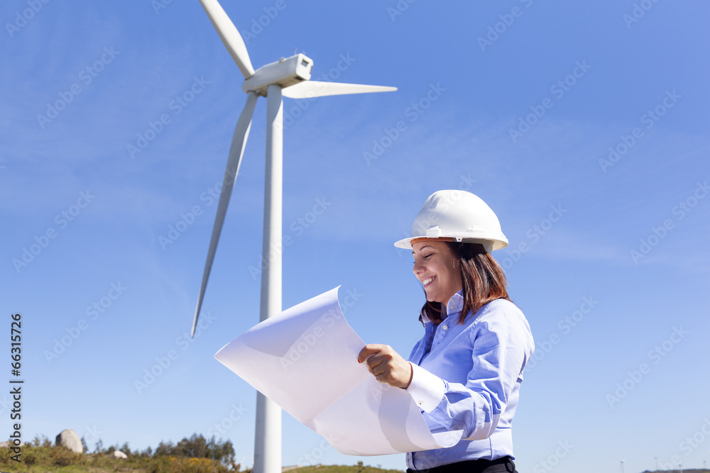 Female engineer holding a blueprints at wind farm Female engineer holding a blueprints at wind farm